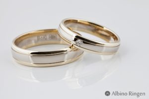 Een volledig glanzende ring gemaakt uit wit- en geelgoud met lijn details en een ronde diamant.